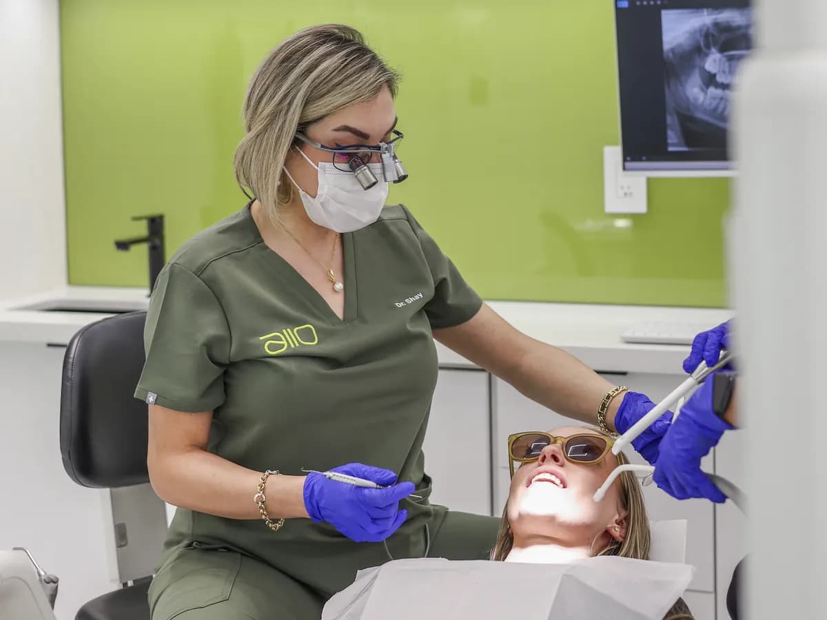 Dr. Shay Rahmatian checking a patient's teeth with a mirror during an exam
