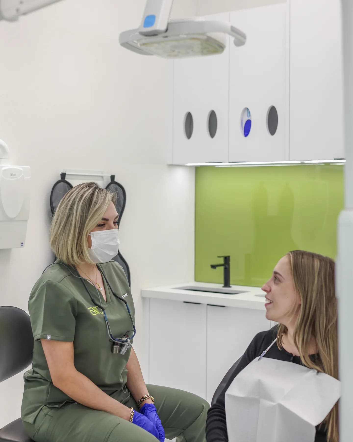 Dr. Shay Rahmatian sitting beside an upright, smiling patient in a treatment room, talking before any treatment begins