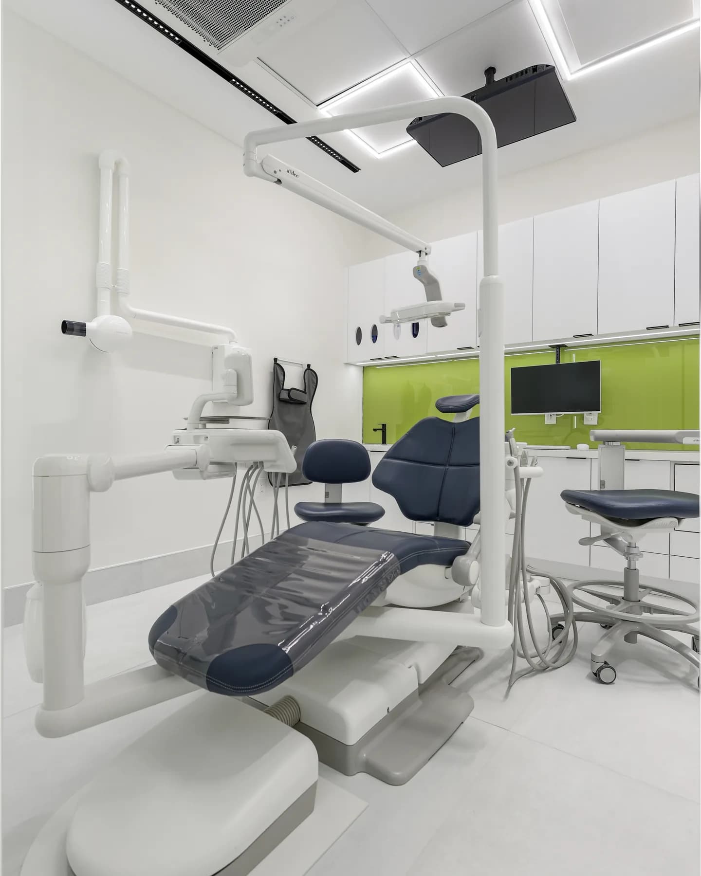 A navy dental chair and X-ray arm in a treatment room at Allo Dental Clinic